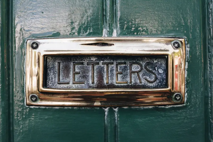Brass letter plate on a painted front door, where the FENSA certificate for a new window job in Exmouth arrives by post