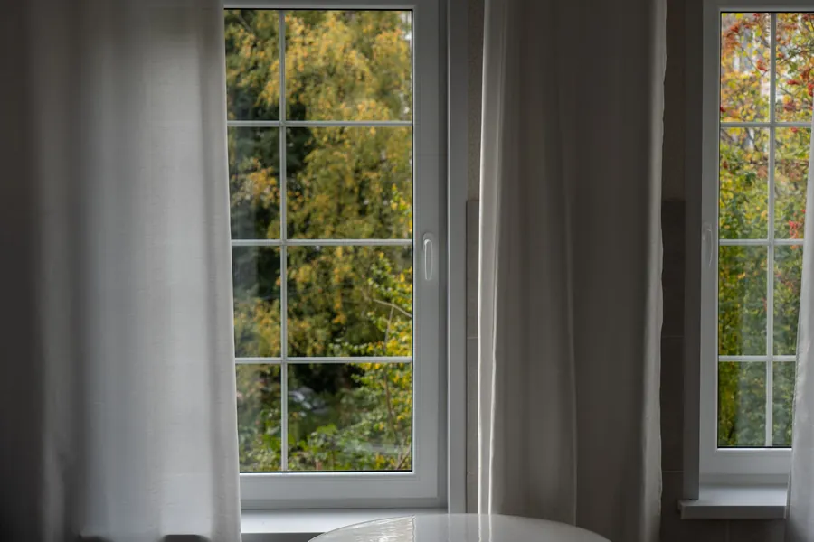 White double-glazed casement windows with glazing bars seen from inside a living room, the standard replacement on Honiton and Ottery estate houses