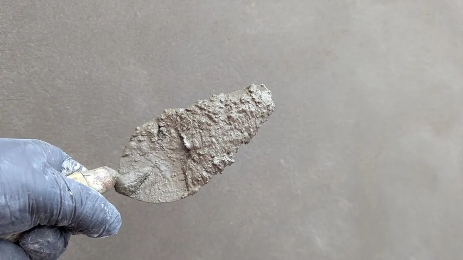 Lime mortar on a pointing trowel ready for making good around a window in an Exeter solid wall