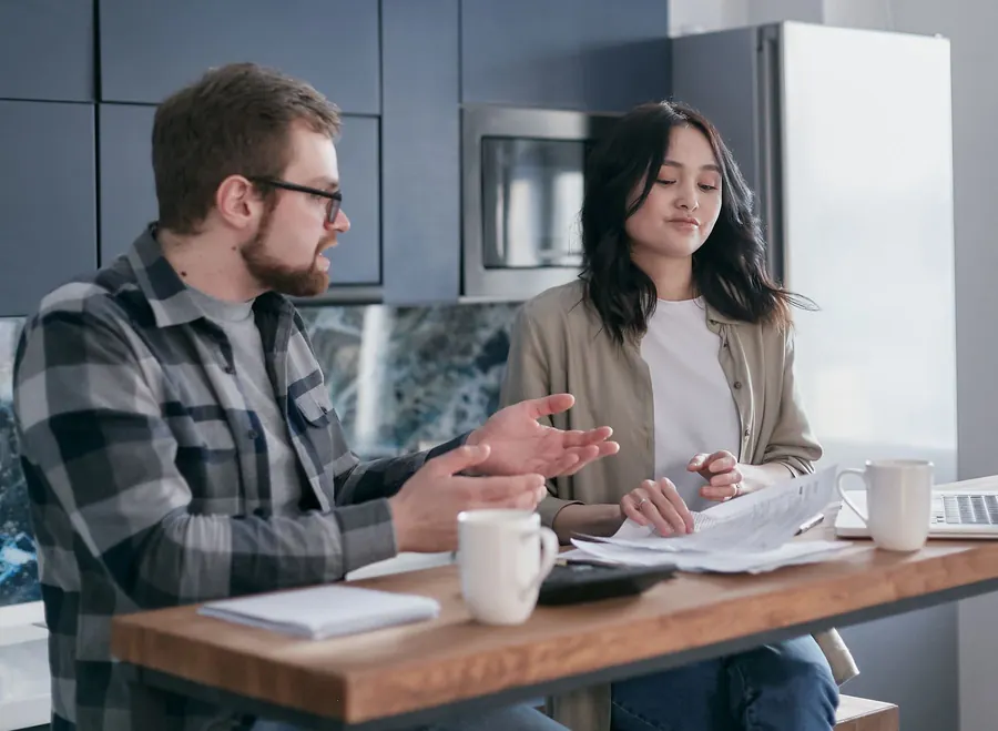 Couple going through building regulations and window certificate paperwork at their kitchen table after new windows in Tiverton