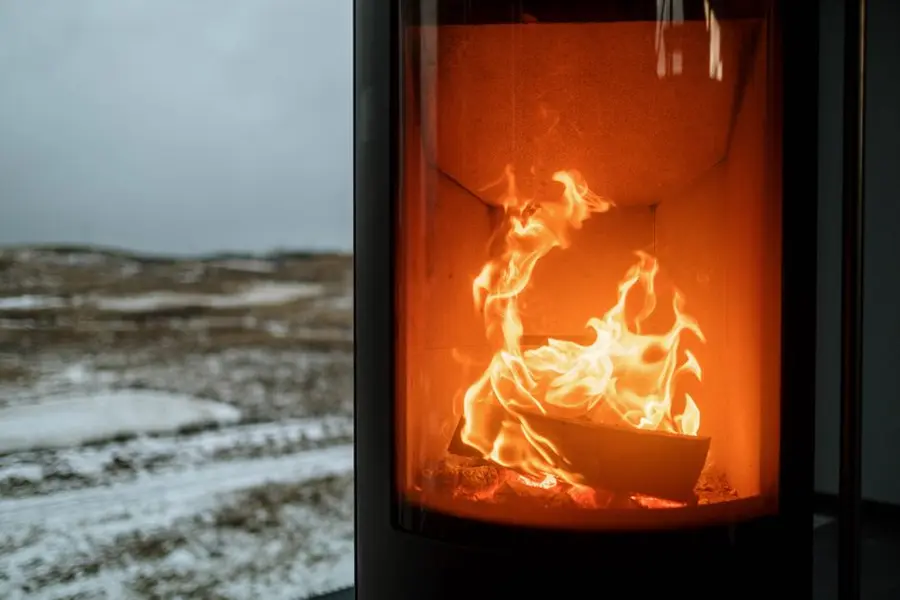 Indoor fireplace with burning flame - energy loss through old windows drives up heating costs in Exeter homes