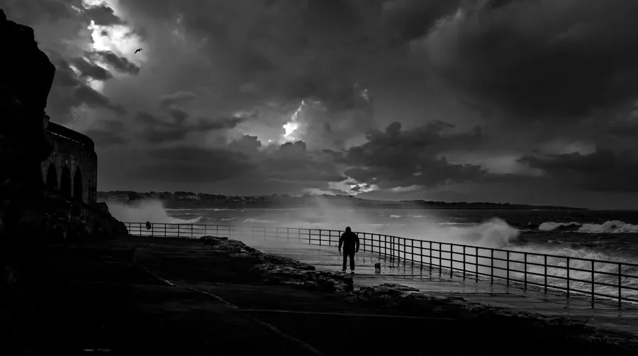 Stormy sea and heavy cloud over an English seafront promenade of the kind that drives wind loading on Exmouth windows