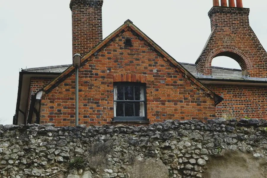 Mixed brick and rubble stone solid wall elevation of the kind that needs individual window survey near Exeter