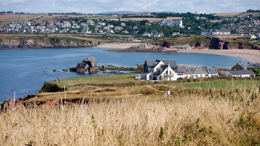 Newer houses spread over the hillside behind a red-cliffed South Devon bay, typical of the later estates where most window replacements are straightforward