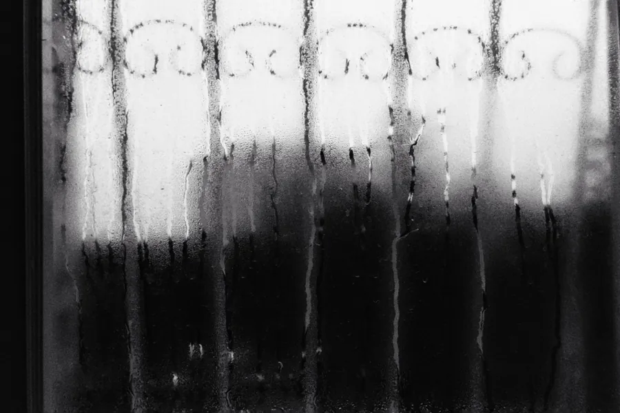 Condensation running down the inside of a patterned window, the problem cold metal frames can cause in damp Exeter winters