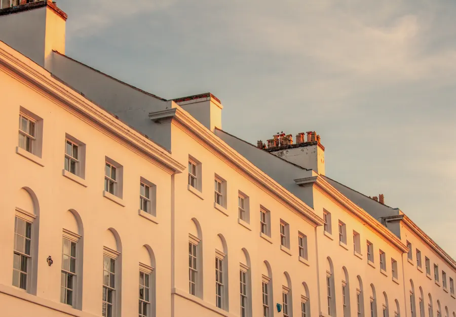 Long cream stucco Regency terrace with matching arched sash windows, the kind of uniform frontage a conservation area aims to protect in Teignbridge
