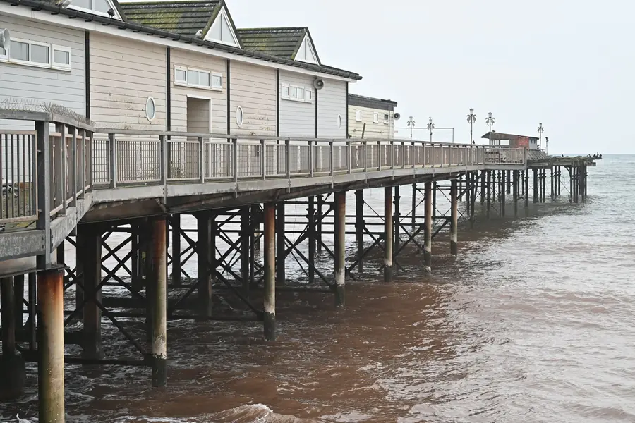 Teignmouth's Grand Pier on its iron legs above the red-tinted water of the seafront, close to the town's Regency streets