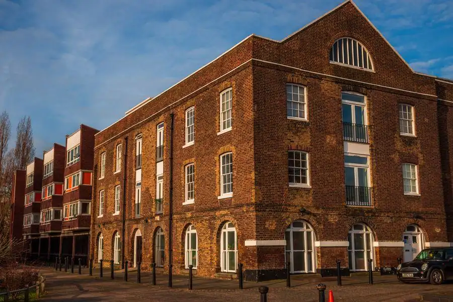 Tall brick waterside warehouse building with rows of white sash windows, similar to the merchants' buildings by the quay at Topsham