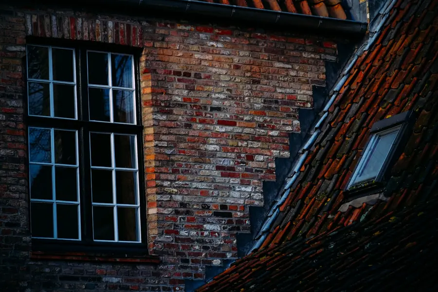 Dark framed casement with white glazing bars set in old brickwork, showing how bar layout decides whether an imitation steel window convinces