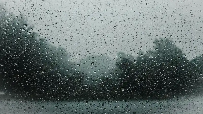 Rain drops running down a window pane on a grey wet day
