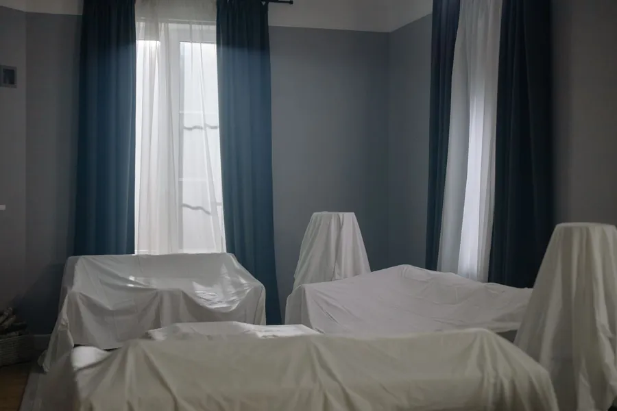 Furniture covered with dust sheets in a room prepared for window fitting in an Exeter home
