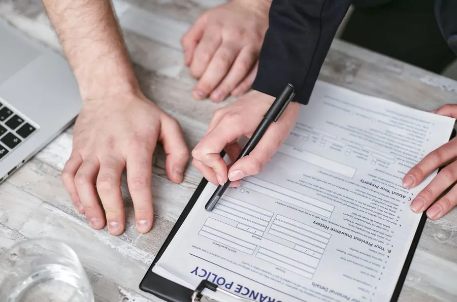 Homeowner signing an insurance-backed guarantee policy document for new windows