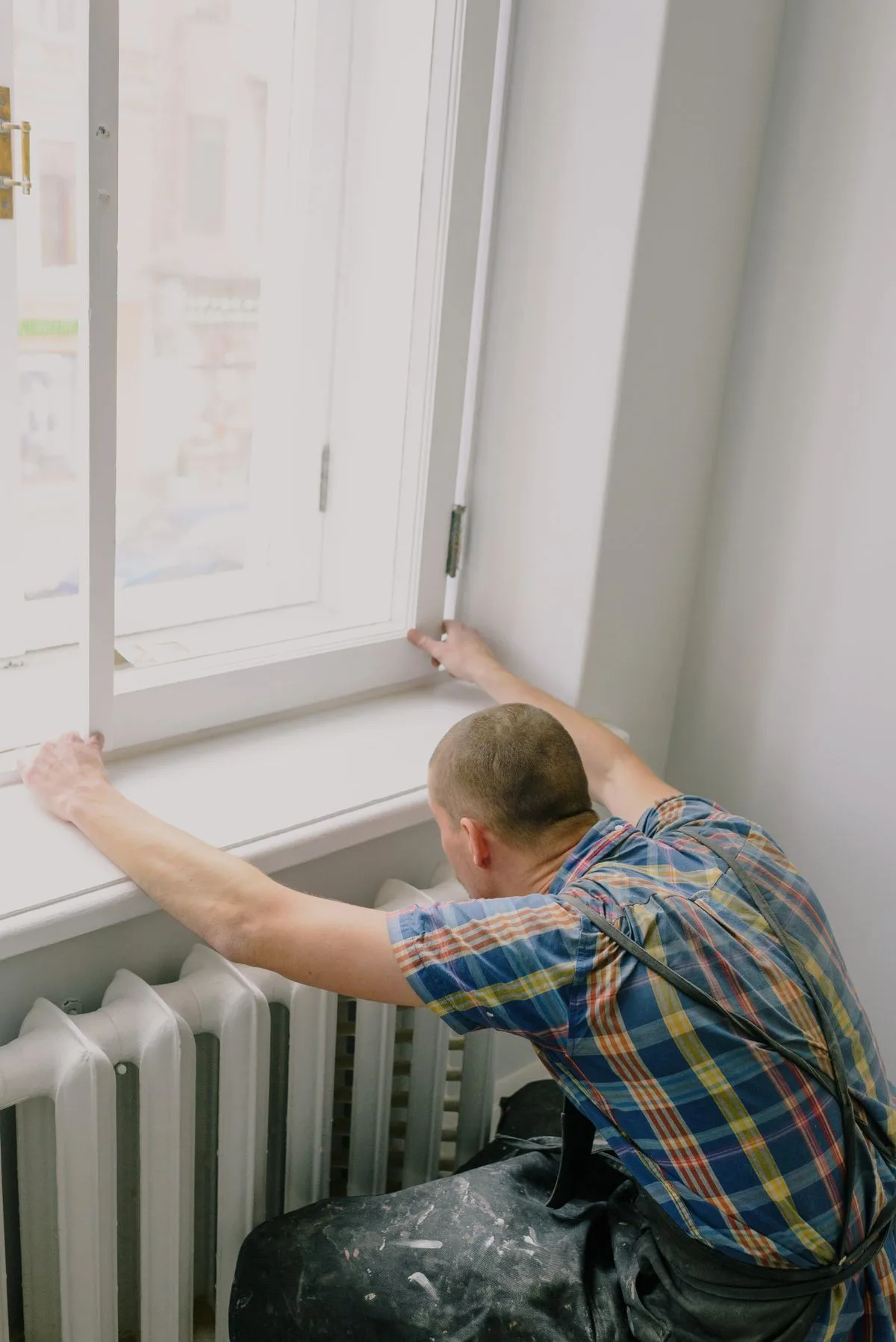 Window fitter installing a uPVC window above a radiator in a Devon property