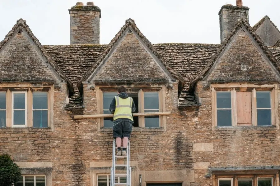 Construction worker removing an old window during home renovation