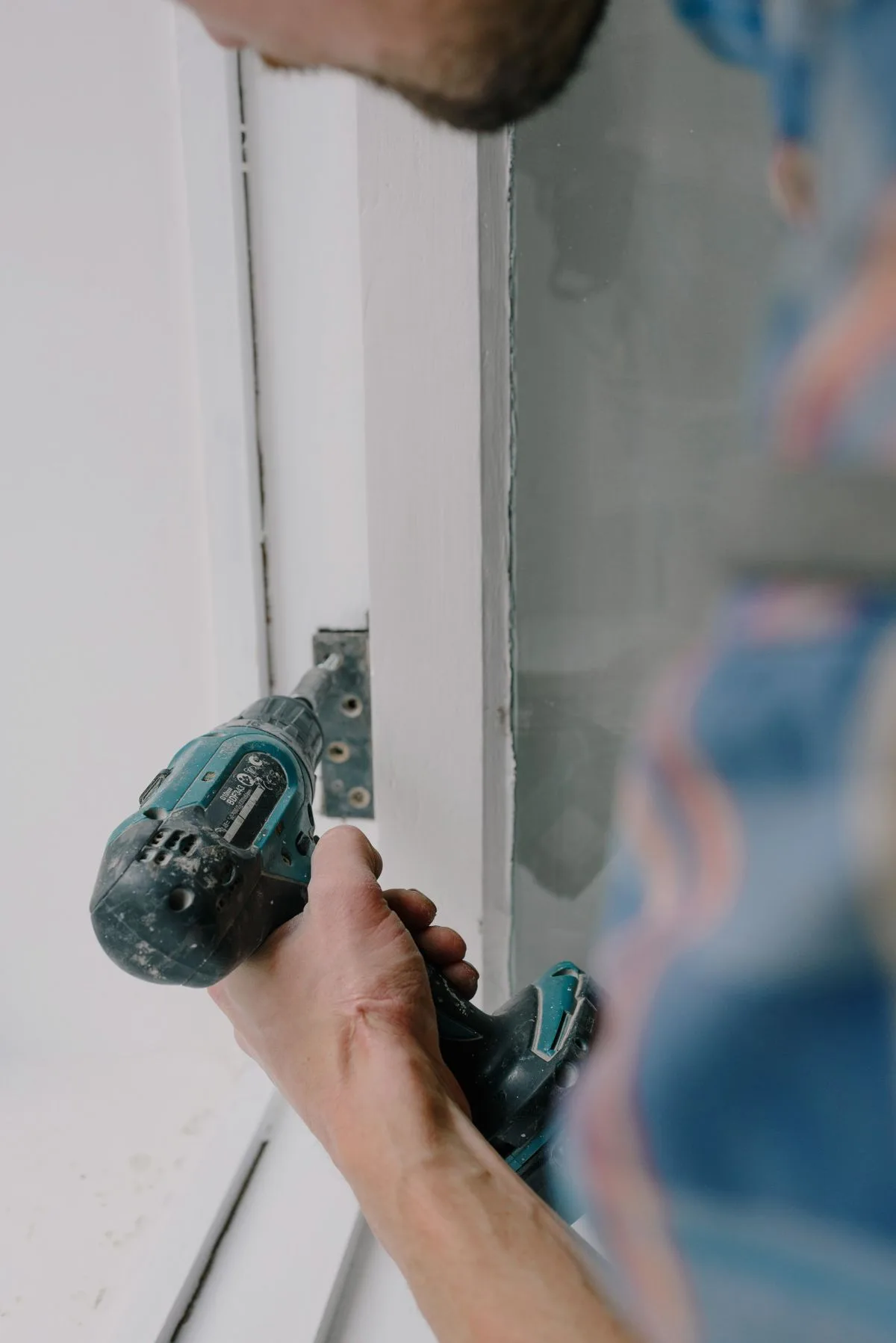 Window installer carefully fitting a new frame in an Exeter property