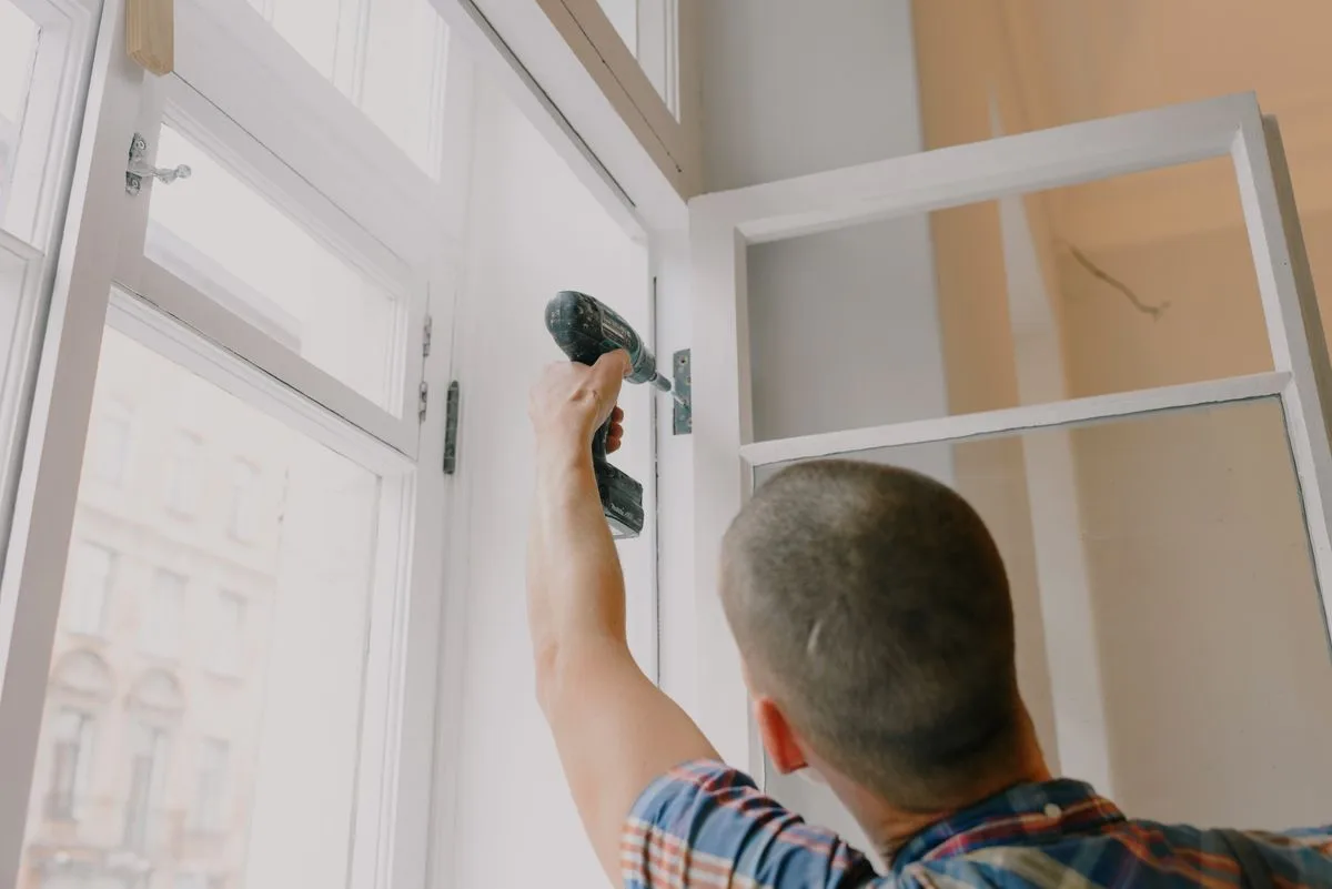 Craftsman fitting a new hinge during window repair in Exeter